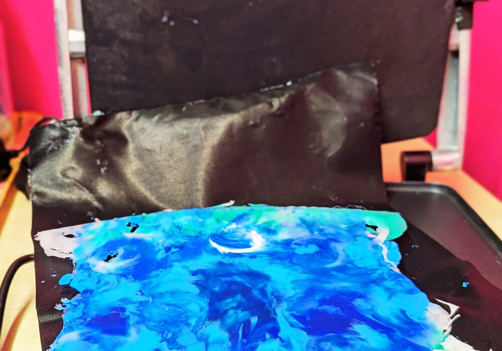 A sheet of blue marbled plastic, made from milk bottle tops, on top of a panini press