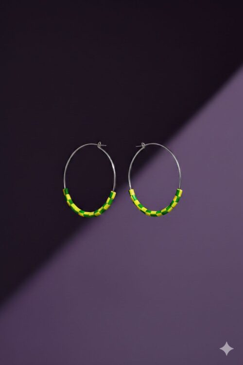 A pair of silver tone hoop earrings with yellow and green beads made from upcycled materials, on a purple background