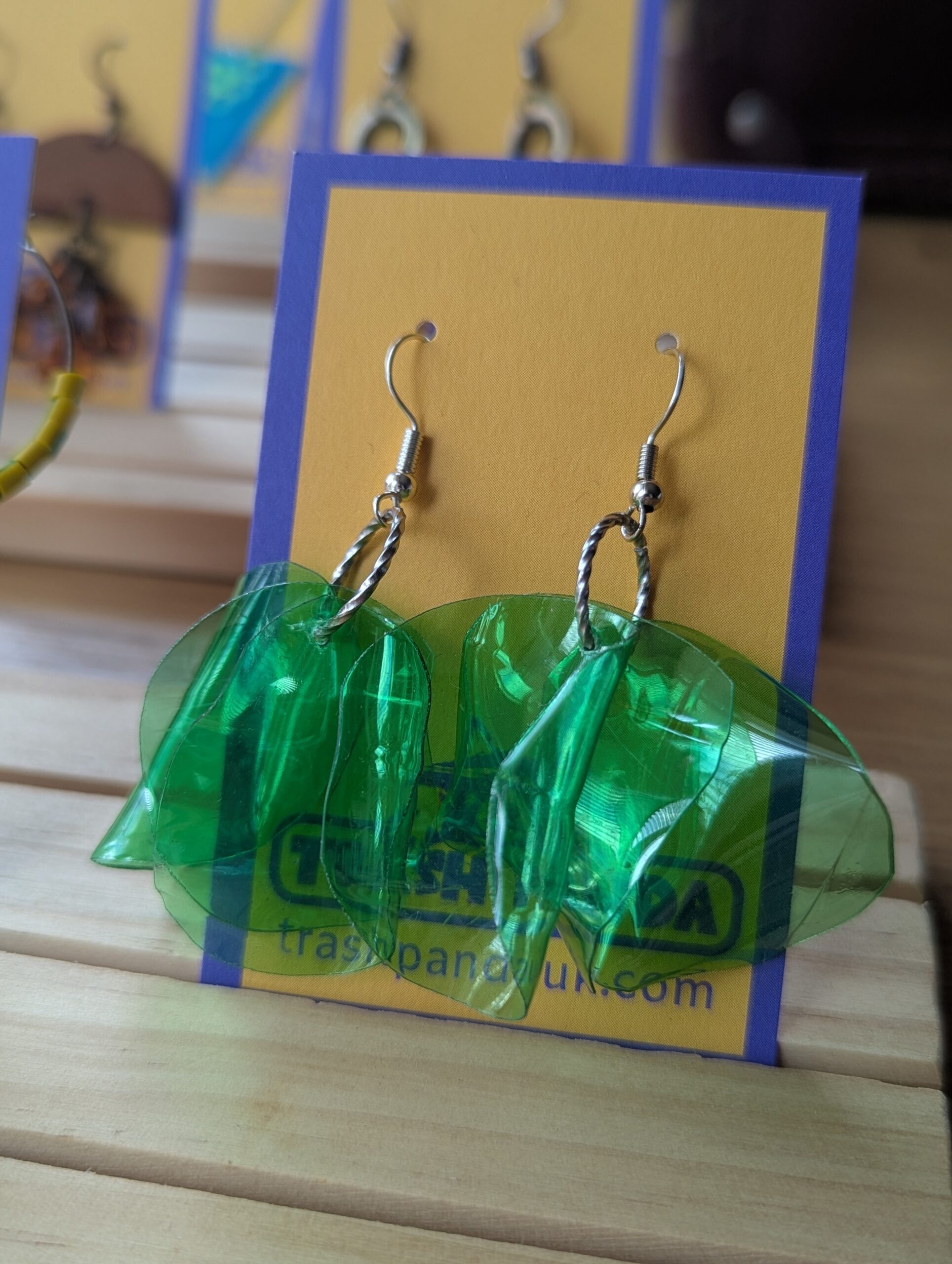 Green upcycled plastic dangly earrings on a jewellery display card
