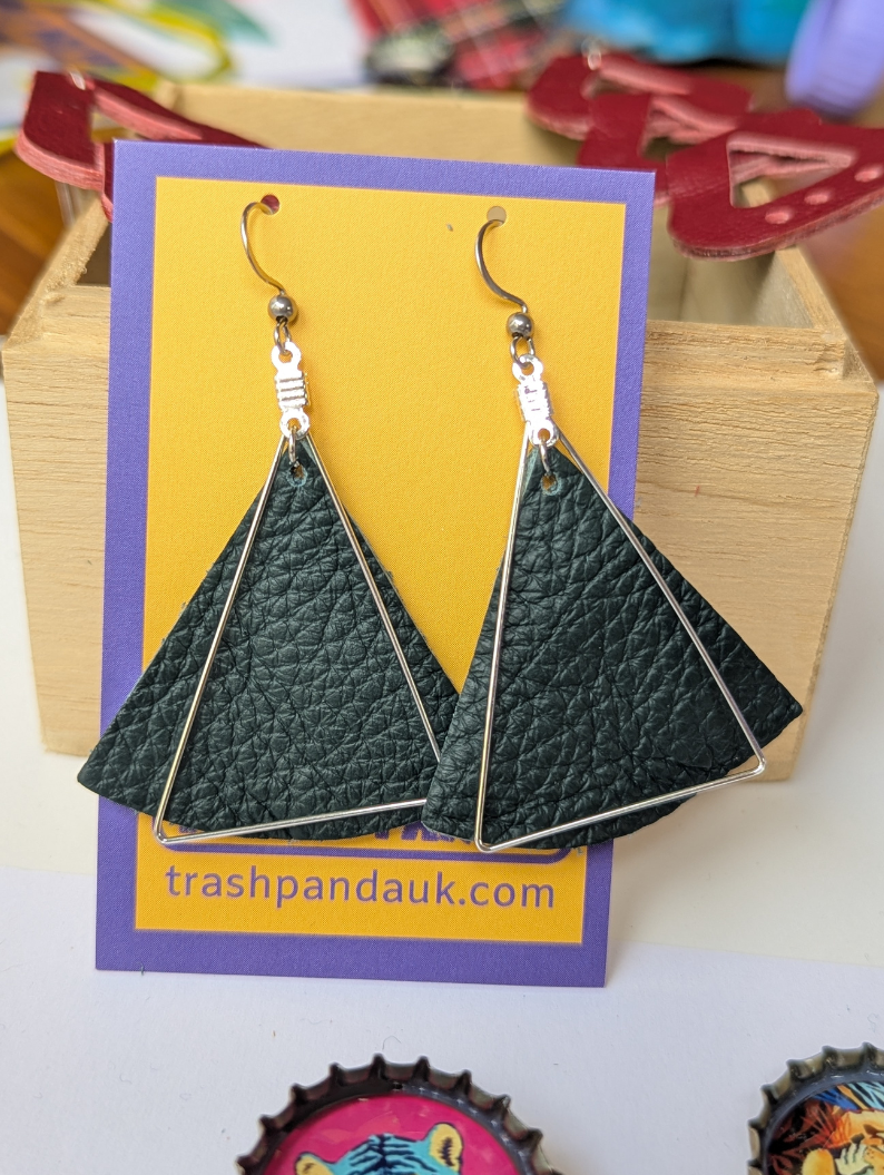 Large dark green leather triangle earrings with silver cut out triangles over top. Displayed on a jewellery card