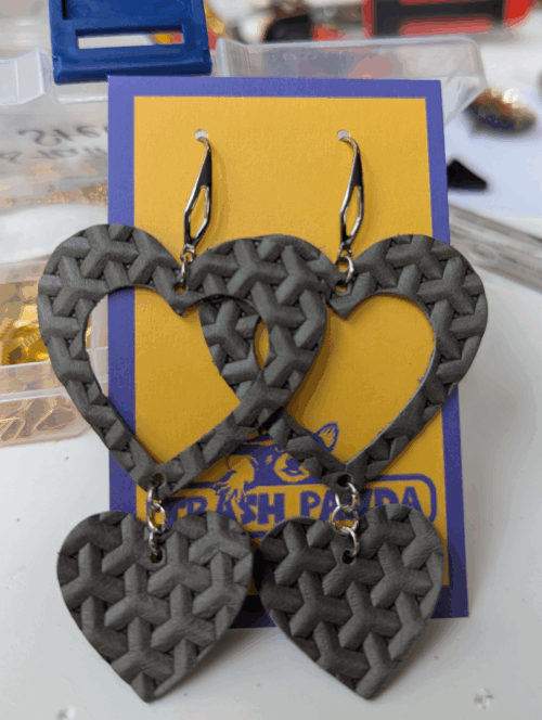 A pair of earrings - in grey basket-weave leather hearts - on a jewellery display card. Handcrafted and upcycled made from recycled materials by Trash Panda UK