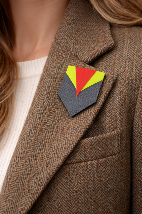 An upcycled brooch made from leather and bouncy castle fragments on a woman's jacket lapel