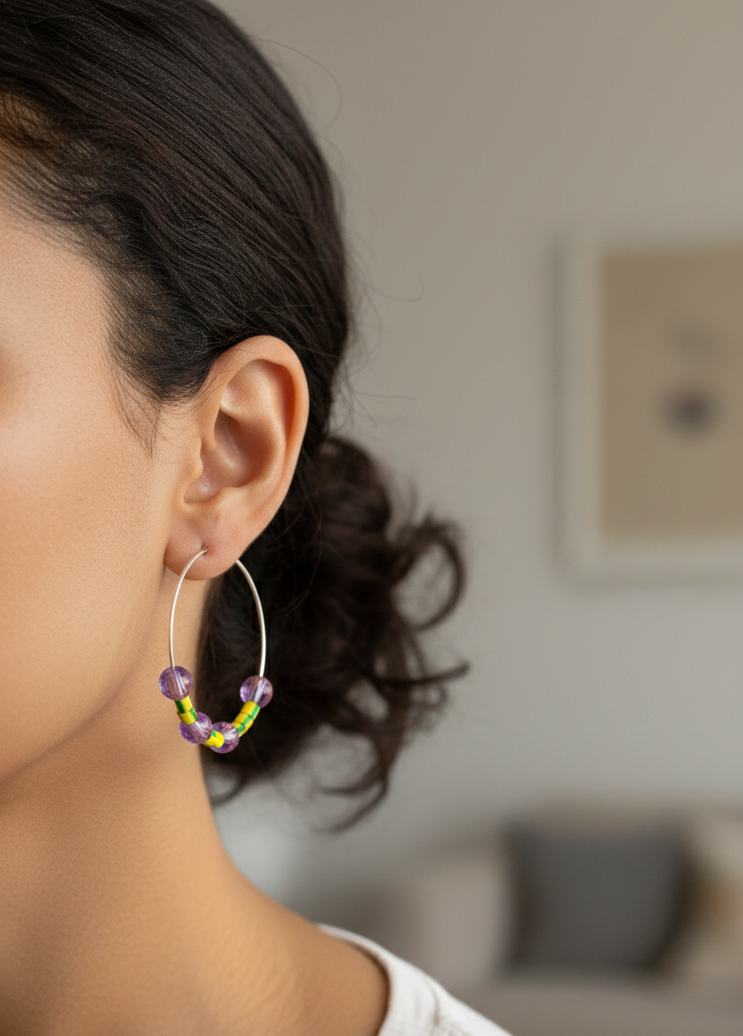 Purple and yellow upcycled hoop earrings on a woman A woman wearing large hoop earrings with lilac and yellow beads. They are made from upcycled electrical wire covers.