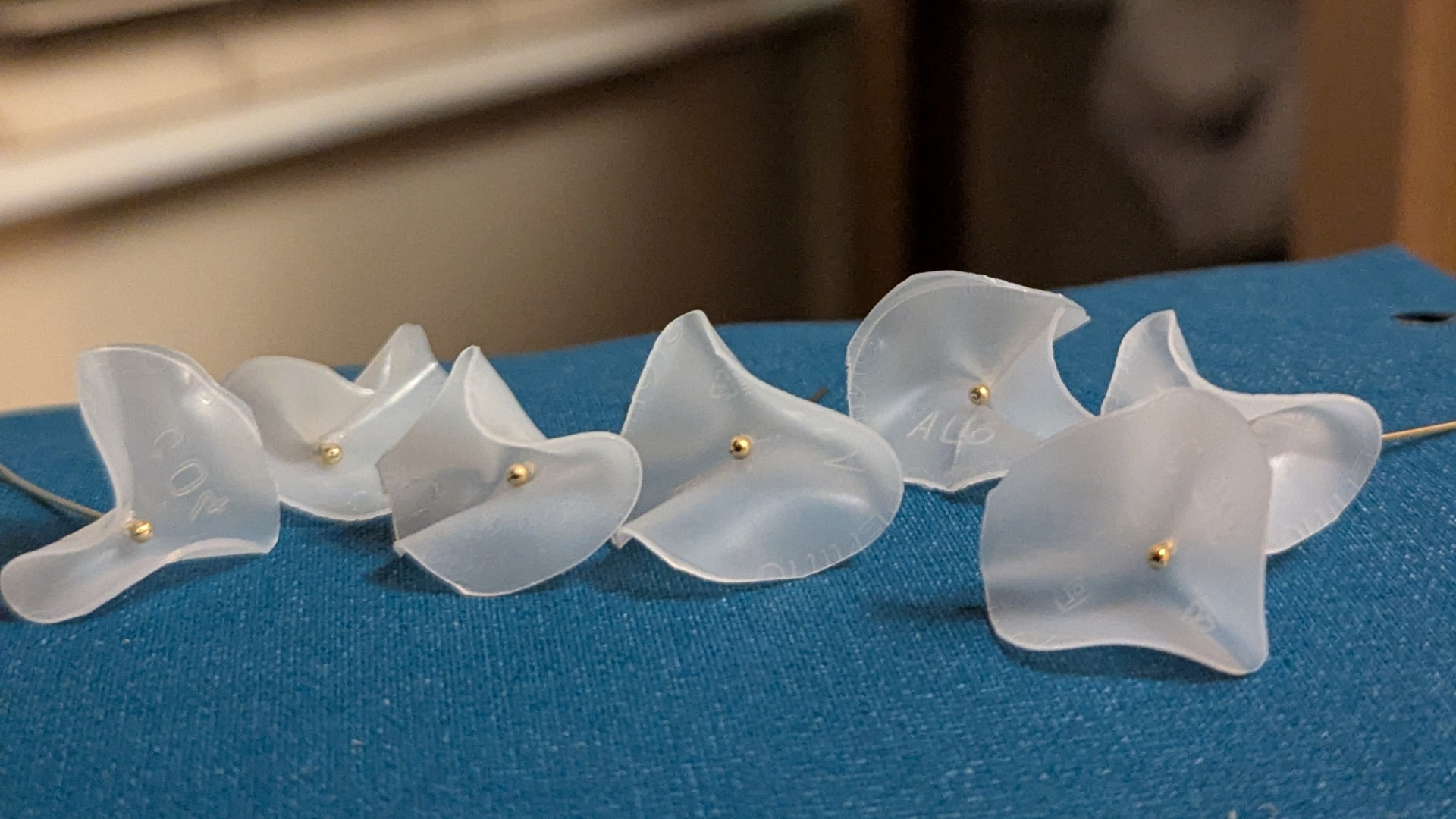 White discs formed into flowers with a gold pin in the centre, set on a blue blanket