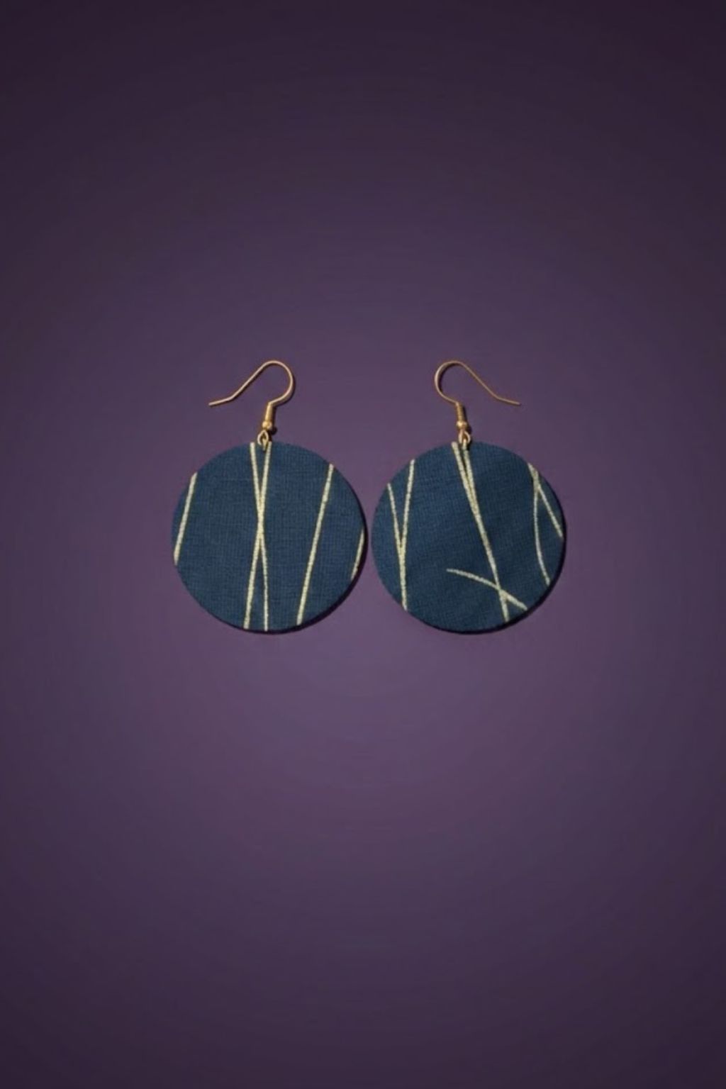 A pair of blue and gold earrings, against a purple backdrop