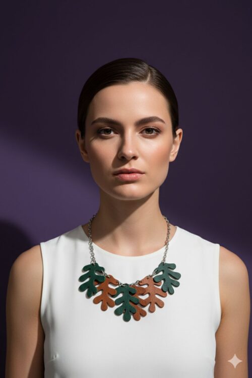 A woman wearing A necklace made from a silver tone chain and oak-shaped leaves cut from leather, on a purple backgound