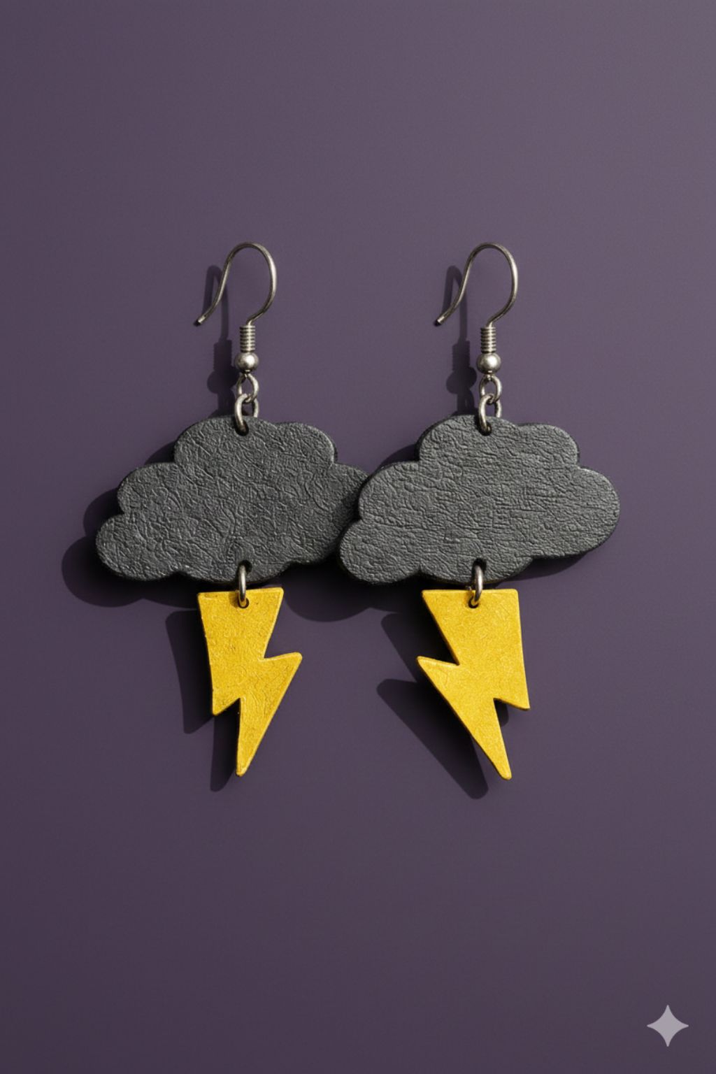 A pair of stormcloud earrings - grey clouds and yellow lightning bolts made of upcycled leather