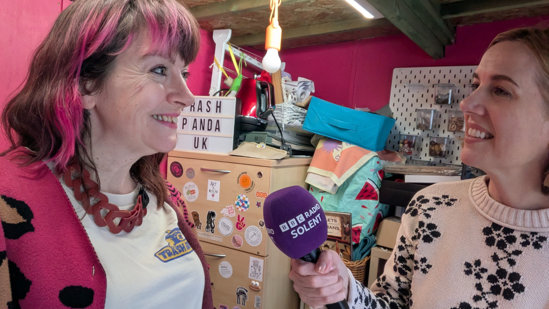 louise-lea-trash-panda-bbc-interview-Southsea A woman being interviewed by another woman for BBC Radio Solent inside a workshop in Southsea